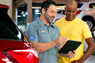 Duas pessoas na oficina Chevrolet verificando a lista de reparos concluídos em um Tablet